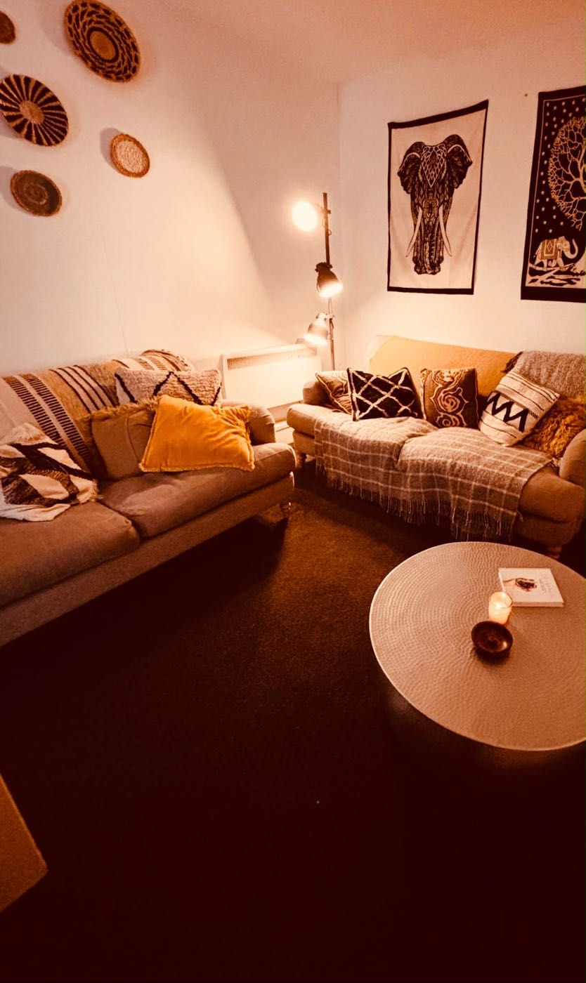 A cosy lounge with two sofas, cushions, throws and a candle on a round table.