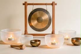 Crystal singing bowls with tealights in front of a gong.